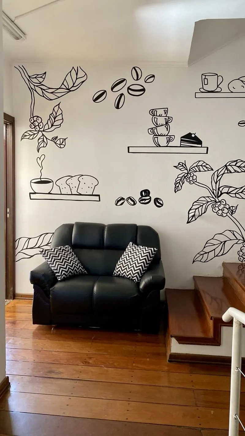 Parede com desenhos de café e pães atrás de poltrona preta