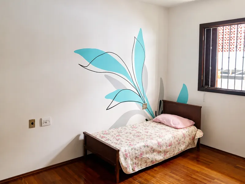 Quarto com cama de solteiro e pintura botânica azul na parede