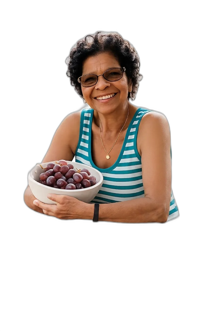 Vó Cida sorrindo, segurando uma tigela com cachos de uvas