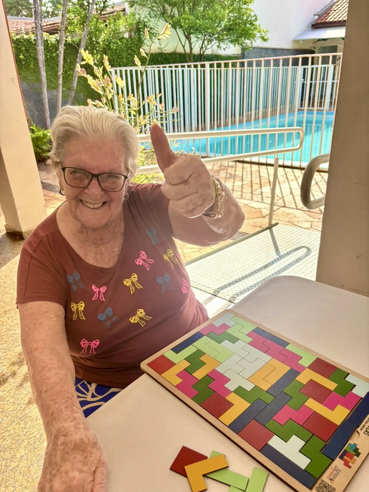 Residente do Vó Cida sorrindo e fazendo sinal de positivo durante atividade de lazer