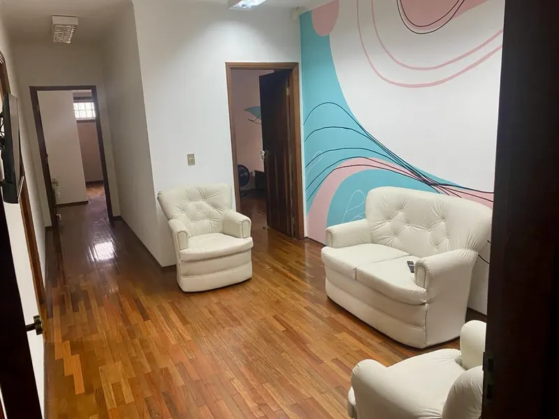 Sala com poltronas brancas e pintura abstrata na parede